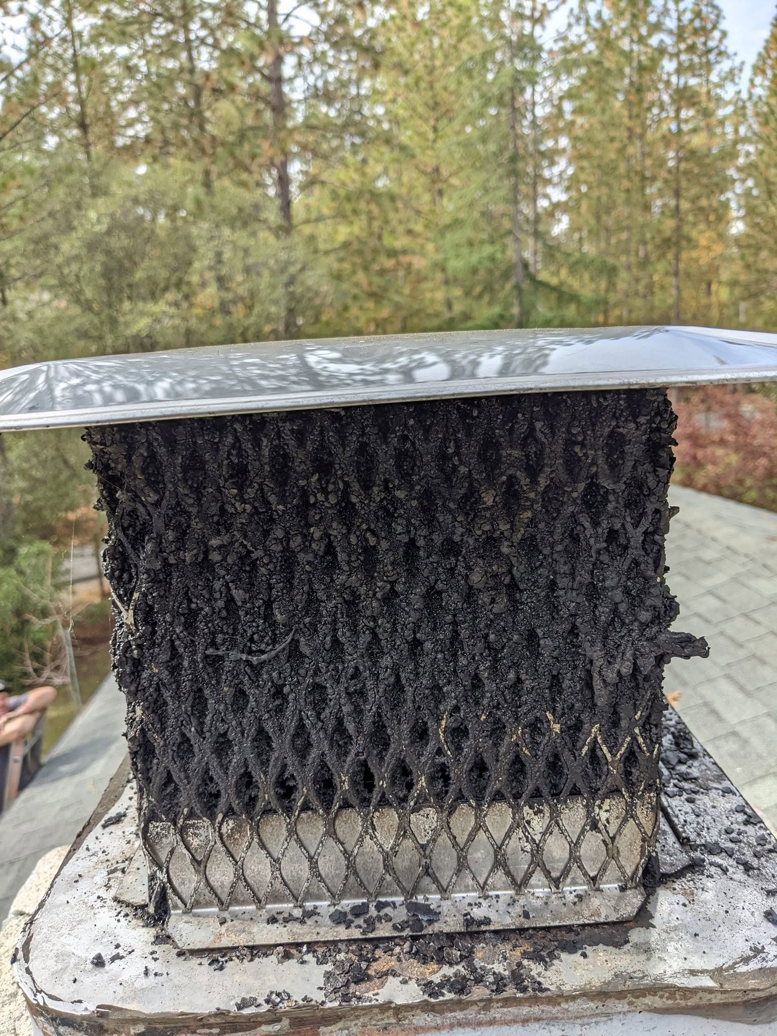 Chimney cap with heavy creosote buildup before cleaning