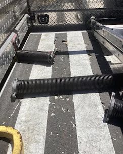 Two garage door torsion springs laid out on a service truck bed