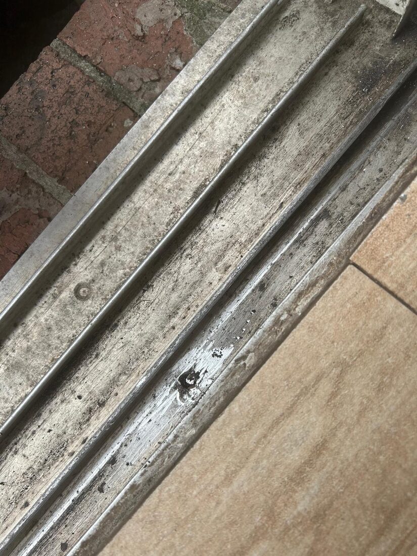 Worn and dirty sliding door bottom track before restoration